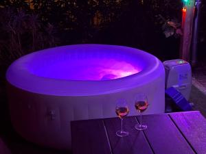 two wine glasses sitting on a table next to a hot tub at Sparkling Time Apartman in Hajdúszoboszló