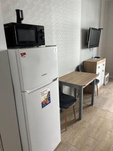 a refrigerator with a microwave on top of it next to a table at Квартира-студія in Odesa