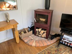 a wood burning stove in a room with a table at Simpers Drift, Great Glemham in Saxmundham