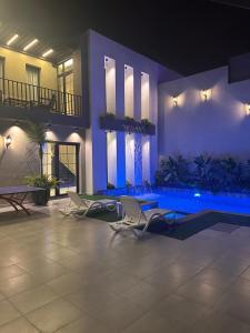 a house with two chairs and a swimming pool at night at TRIO Chalet 2 in Sowayma