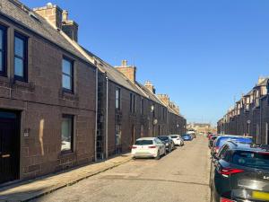 a street with cars parked next to brick buildings at Almanythie Snug, Peterhead in Peterhead