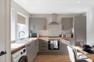 a kitchen with white cabinets and a table with chairs at Almanythie Snug, Peterhead in Peterhead