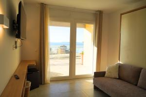 a living room with a couch and a sliding glass door at Hôtel-Club du Domaine d'Aiguebelle, USSIM Vacances in Le Lavandou