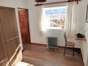 Habitación con puerta, silla y ventana en Andean Spirit Apartments, en Cusco