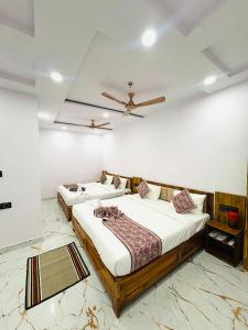 a bedroom with two beds and a ceiling fan at Hotel Shiva Darshanam in Varanasi +9 photos