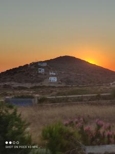 a sunset over a hill with houses on a hill at Cycladic residence, Saint George, Antiparos in Agios Georgios
