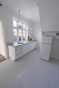 a white kitchen with a sink and a refrigerator at Kysthus Villa Nexø in Neksø