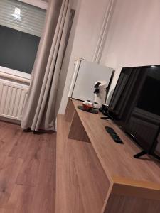 a living room with a television and a wooden table at Le Petit Refuge de Malmedy in Malmedy