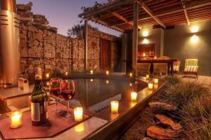 a pool with wine glasses and candles and a bottle of wine at 17 Marine - Apt 103 - Private Hot Tub & Garden in Hermanus
