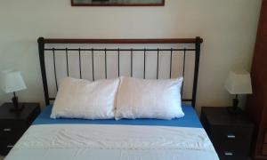 a bed with two pillows on it with two lamps at Apartment Skroza in Žirje