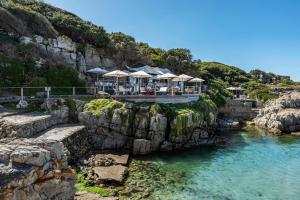 a restaurant on a cliff next to a body of water at 17 Marine - Apt 103 - Private Hot Tub & Garden in Hermanus