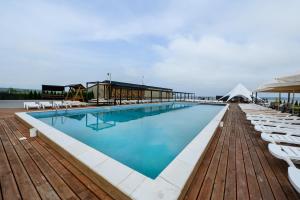 a large swimming pool on a wooden deck with white lounge chairs at California Resort and SPA in Novoyavorivsk