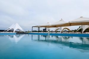 a swimming pool with white umbrellas and tables at California Resort and SPA in Novoyavorivsk