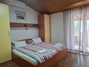 a bed in a room with a large window at Apartmani Tomić in Seline