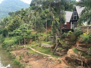 a house on a hill next to a river at Kithulgala Cabana Resort in Kitulgala +11 photos