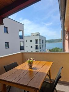 a wooden table on a balcony with a view of the water at Apartmani Tomić in Seline