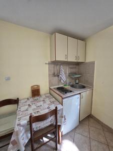 a kitchen with a stove and a sink and a table at Apartmani Dado in Sutomore