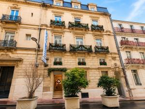 a building with potted plants in front of it at Hotel Comédie - Place De La Comédie Opéra in Montpellier