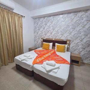 a bedroom with a bed with an orange blanket and yellow pillows at Villa Helga Exotic in Pefkochori