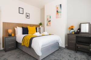 a bedroom with a bed with yellow pillows and a desk at Heath Lodge in Stockingford