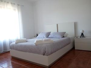 a bedroom with a bed with two towels on it at PoolSeaView Spacious House in Atouguia da Baleia