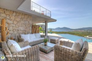 a patio with wicker furniture and a stone wall at La lunera in Porticcio