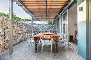 a wooden table and chairs on a patio with a stone wall at 17 Marine - 2 Bedroom - Garden - Apt 104 in Hermanus