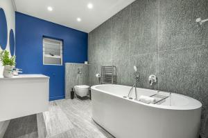 a bathroom with a white tub and a blue wall at 17 Marine - 2 Bedroom - Garden - Apt 104 in Hermanus +22 photos