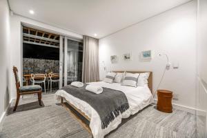a bedroom with a large bed and a dining room at 17 Marine - 2 Bedroom - Garden - Apt 104 in Hermanus