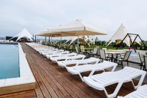 a row of white chairs and umbrellas next to a pool at California Resort and SPA in Novoyavorivsk +60 photos