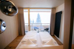 a bedroom with a bed in front of a large window at Bio-Berghotel Ifenblick in Balderschwang
