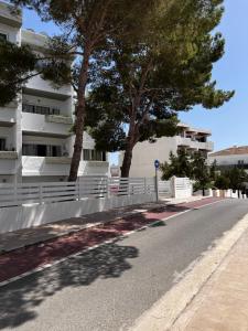 a street in front of a white building with trees at ED REXII ático in Es Pujols