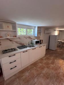 a kitchen with white cabinets and a sink and a refrigerator at Résidence Les Camélias in Tabarka