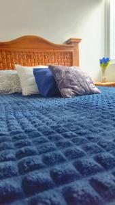 a bed with a blue comforter and pillows on it at Estadio GNP and Airport AICM in Mexico City