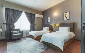 a hotel room with two beds and a chair at Hillside Residence E-7 by Paramount Hospitality in Islamabad