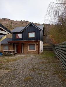 a house with a black roof and a fence at Casas Nahuilen in San Martín de los Andes