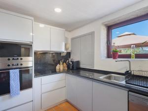 a kitchen with white cabinets and a sink and a window at Quinta do Avô - Casa de Campo in Terras de Bouro