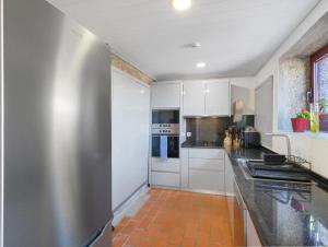 a kitchen with white cabinets and a stainless steel refrigerator at Quinta do Avô - Casa de Campo in Terras de Bouro