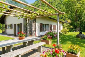a wooden bench in front of a house with flowers at Casa Mima Chalets in Gerra Verzasca +70 photos