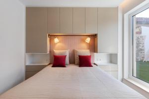 a bedroom with a bed with red pillows and a window at Vila Santa Luzia 4 in Fátima +12 photos