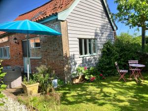 a house with a blue umbrella in the yard at Simpers Drift, Great Glemham in Saxmundham