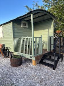 a large green shed with a staircase and a porch at Shepherds Rest in Peak Forest +2 photos