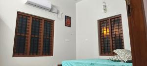 a room with two windows and a green bed at NilaTheeram in Trivandrum