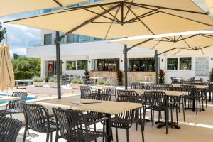 an outdoor patio with tables and chairs and umbrellas at THB Dos Playas - Adults Only in Cala Ratjada