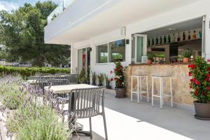 a patio with tables and chairs and a bar at THB Dos Playas - Adults Only in Cala Ratjada