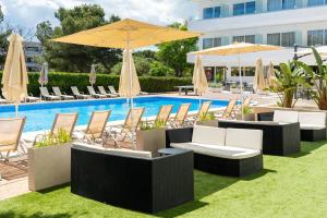 a pool with lounge chairs and umbrellas next to a pool at THB Dos Playas - Adults Only in Cala Ratjada