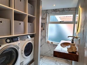 a bathroom with a washing machine and a sink at B&B The White House in Westzaan