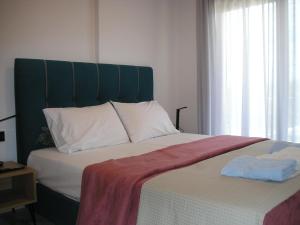 a bed with a green headboard and two towels on it at Golden Beach Inn in Chrysi Ammoudia