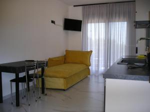 a living room with a yellow couch and a table at Golden Beach Inn in Chrysi Ammoudia