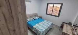 a bedroom with a bed with a blue comforter and a window at Villa in Ouled Yaneg in Ouled Yaneg
